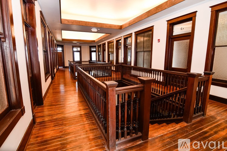 A long hallway with wood floors and a balcony.