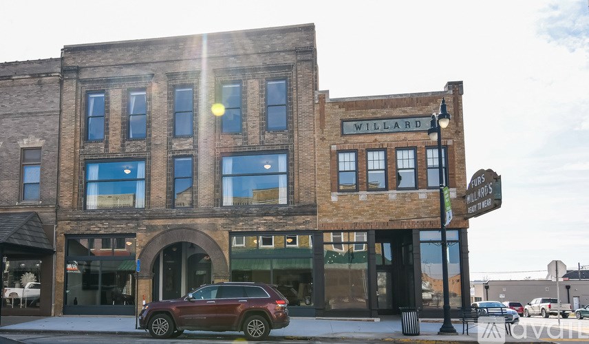 A brown car is parked in front of a Willard building.