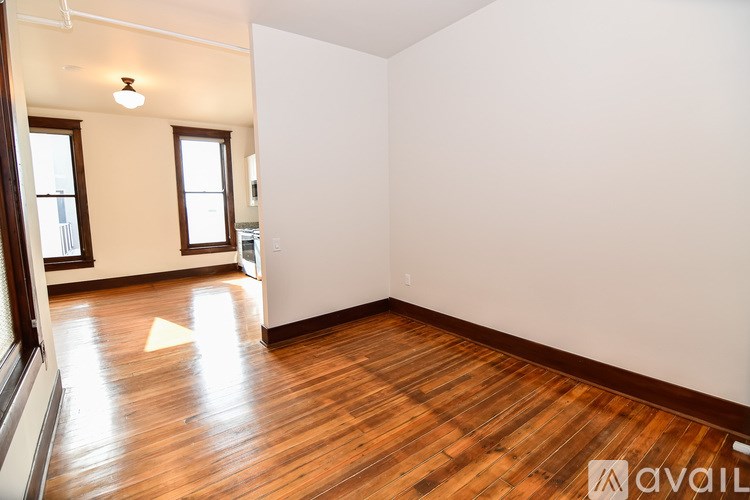 A room with wooden floors and white walls is available for rent.