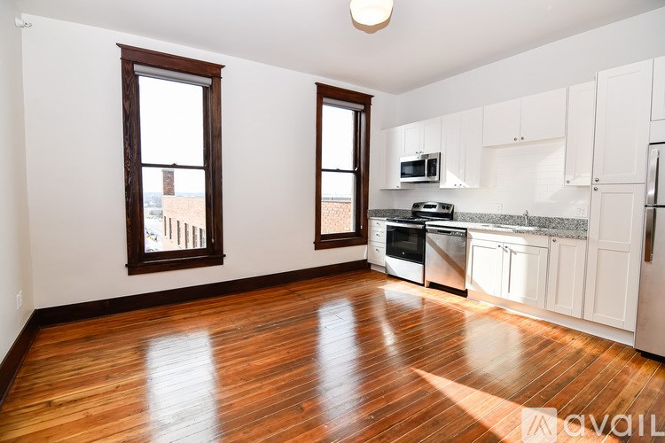 A kitchen with white cabinets and a wooden floor.