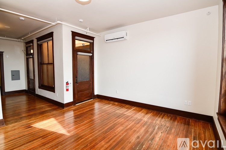 A room with wooden floors and a white wall with a door and a window.