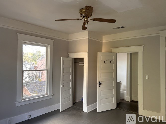 A room with a ceiling fan and a window showing an outdoor view.