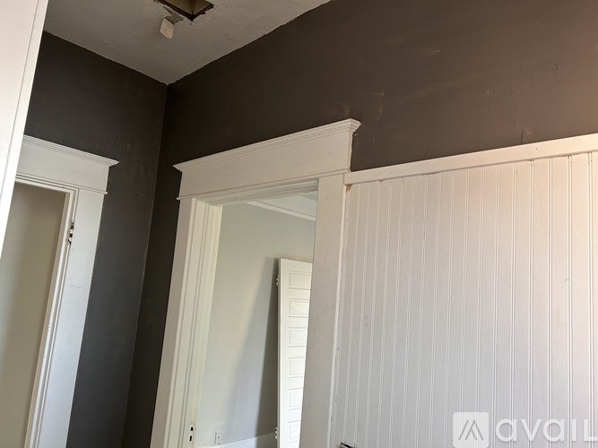 A room with a white door and a grey wall.