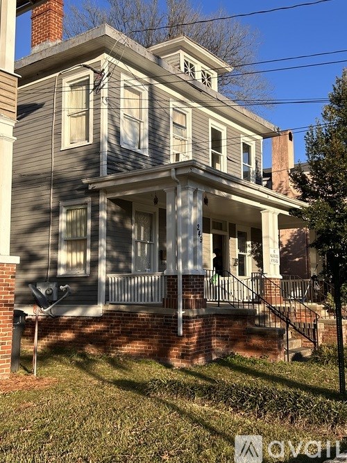 A grey house with a white porch and a mailbox on the left.