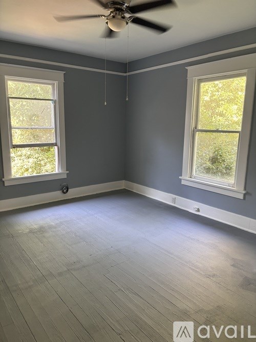 A room with a ceiling fan and two windows.