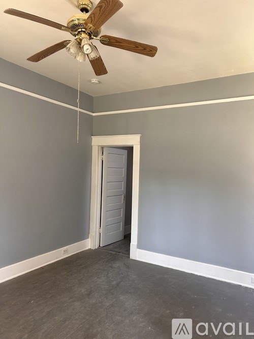 A room with a ceiling fan and a door.