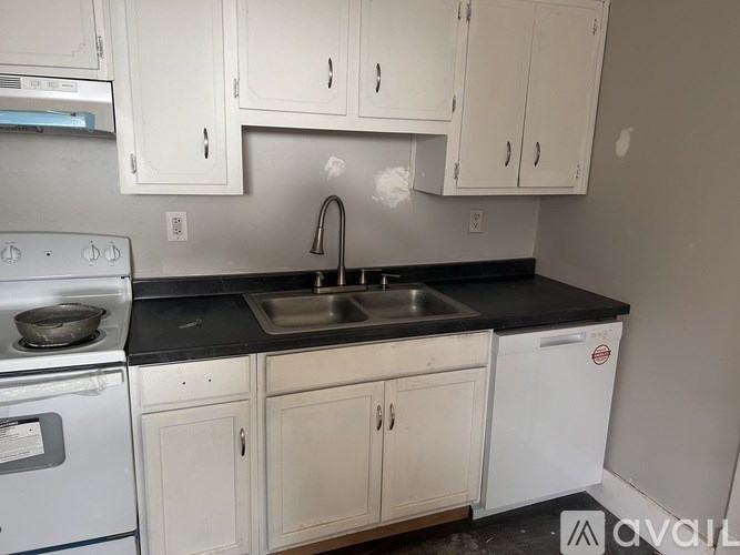 A kitchen with white cabinets and black countertops.