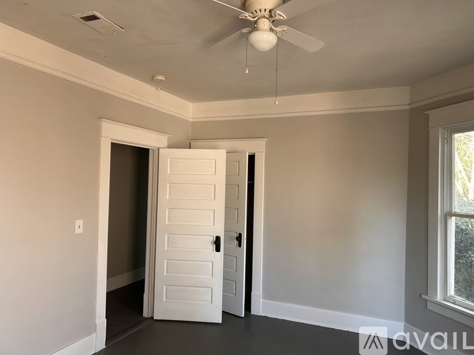 A room with a white door and a ceiling fan.