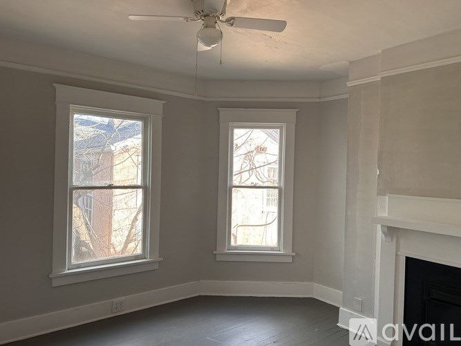 A room with two windows and a fireplace.