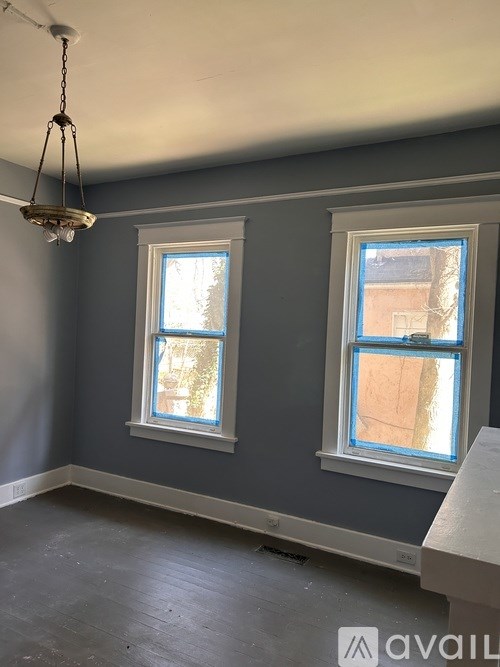 A room with two windows and a chandelier hanging from the ceiling.