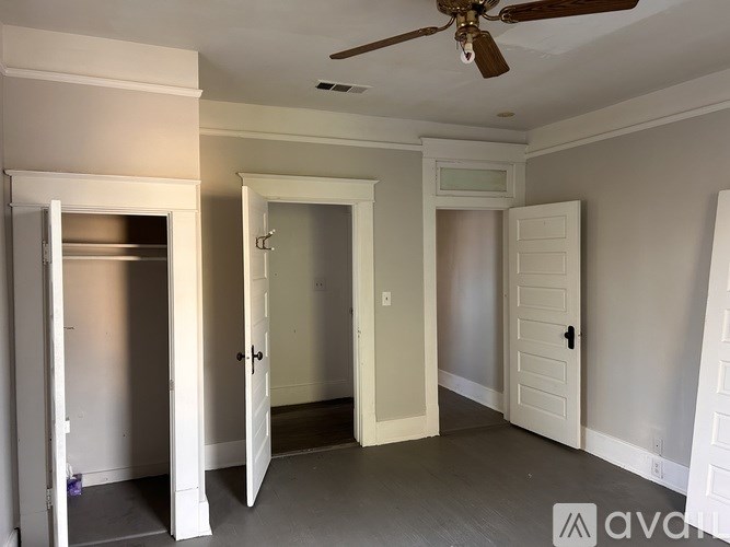 A room with a ceiling fan and three doors.