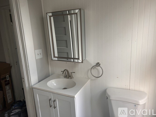 A white bathroom with a sink, mirror, and toilet.