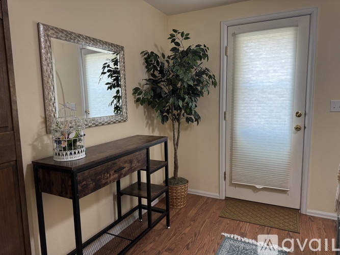 A mirror, a potted plant, and a wooden table with a vase on it.