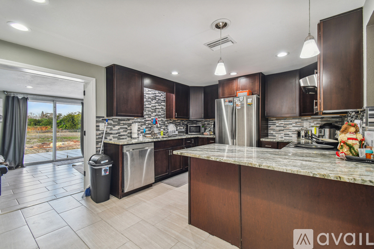 A modern kitchen with dark brown cabinets and a marble countertop.