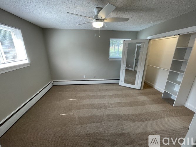 A room with a carpeted floor and a ceiling fan.
