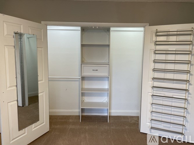 A white closet with a mirror and shelves.