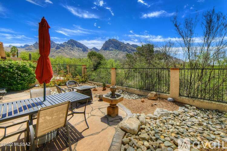 A patio with a table, chairs, and a fountain with mountains in the background.