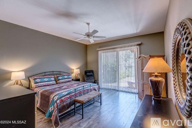 A bedroom with a bed, a fan, and a chair.