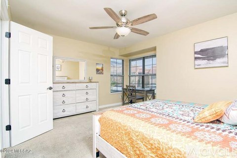 A bedroom with a bed, dresser, and ceiling fan.