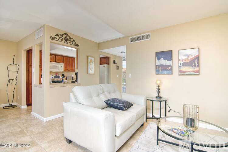 A living room with a white couch and a glass coffee table.