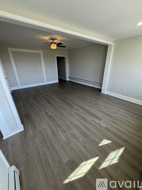 A spacious room with wooden flooring and a ceiling fan.