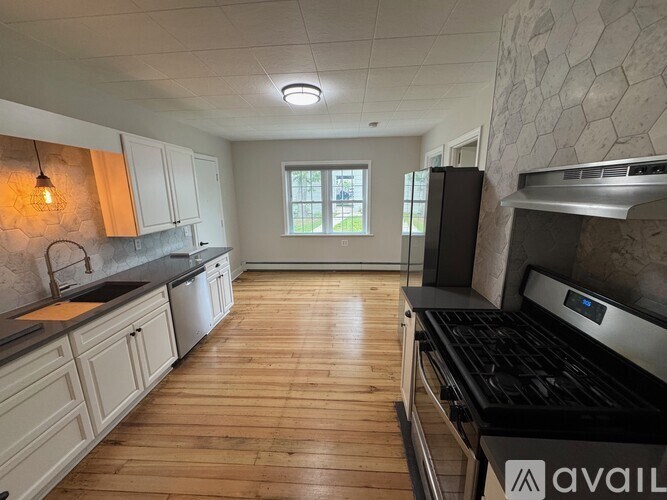 A kitchen with wooden floors and a black stove top oven.