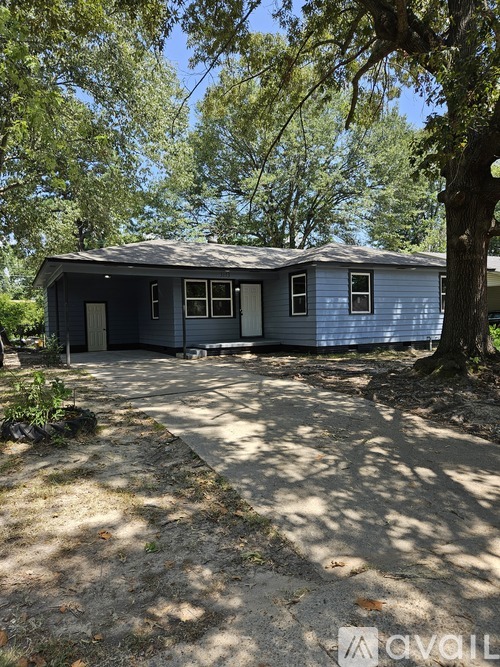 A blue house with a grey roof is surrounded by trees.
