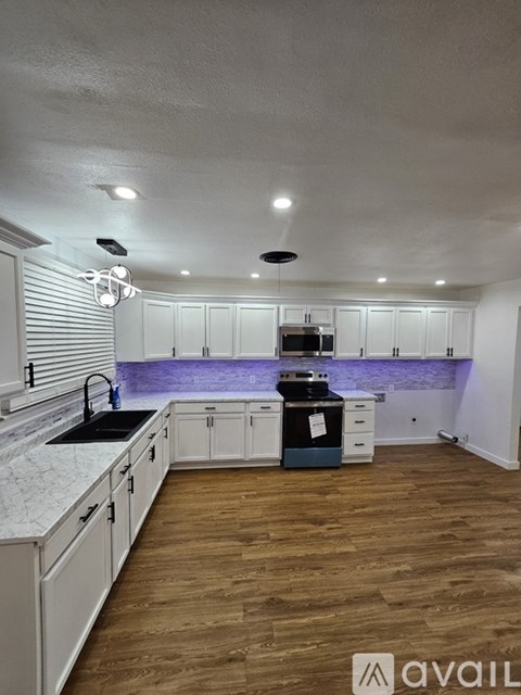 A kitchen with white cabinets and a wooden floor.