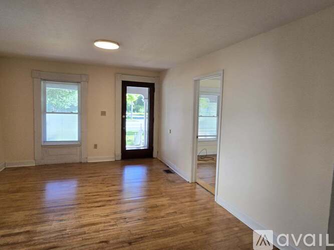 A room with wooden floors and a door leading to a balcony.