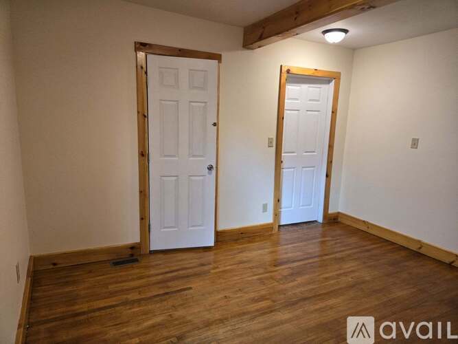 A room with two white doors and wooden floors.