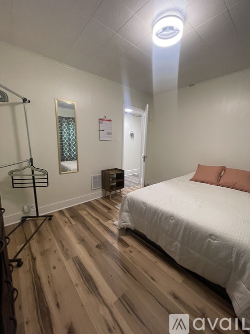 A bedroom with a bed, a chair, and a rug with black crosses on it.