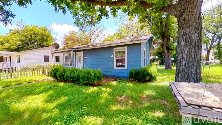 A blue house with a white fence and a tree in front.