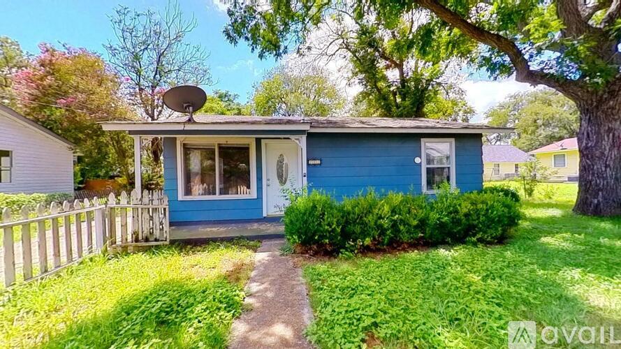 A blue house with a white fence and a satellite dish on the roof.