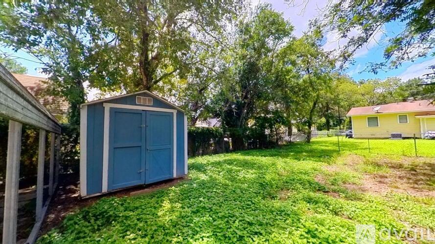 A blue shed sits in a grassy yard.