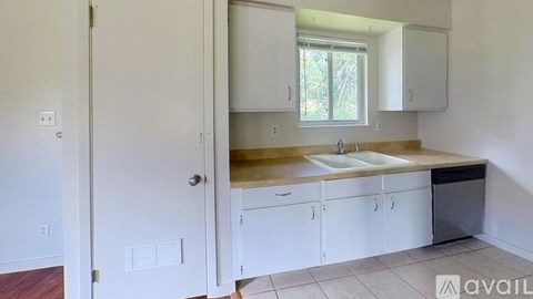 A kitchen with white cabinets and a window above the sink.