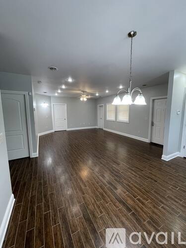 A room with wooden flooring and a chandelier hanging from the ceiling.