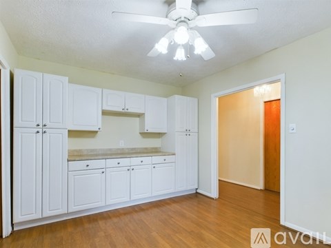 A kitchen with white cabinets and a ceiling fan.