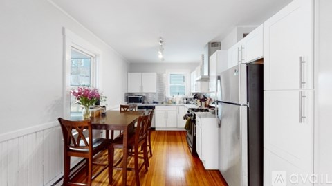 A kitchen with white cabinets and a wooden table.
