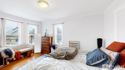 A bedroom with a bed, dresser, and window.