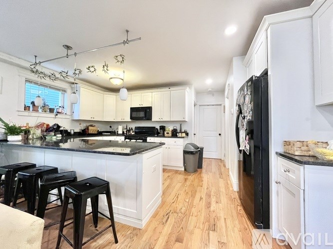 A kitchen with white cabinets and black appliances.