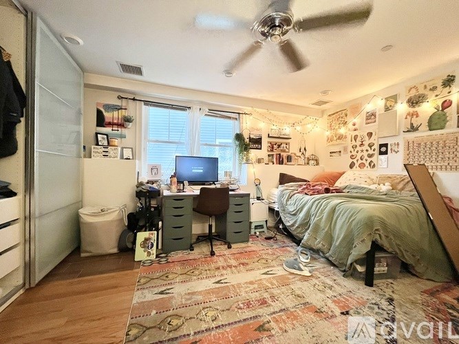 A bedroom with a bed, desk, and a ceiling fan.