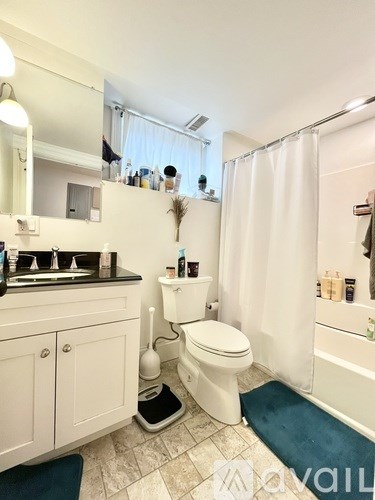 A white toilet is in a bathroom with a white shower curtain.