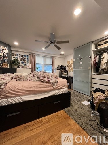 A bedroom with a bed, a ceiling fan, and a wardrobe.