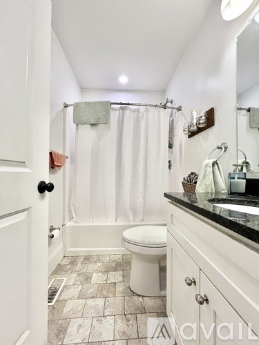 A white bathroom with a toilet, sink, and shower.