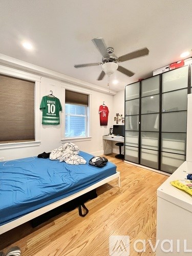 A bedroom with a bed, desk, and ceiling fan.