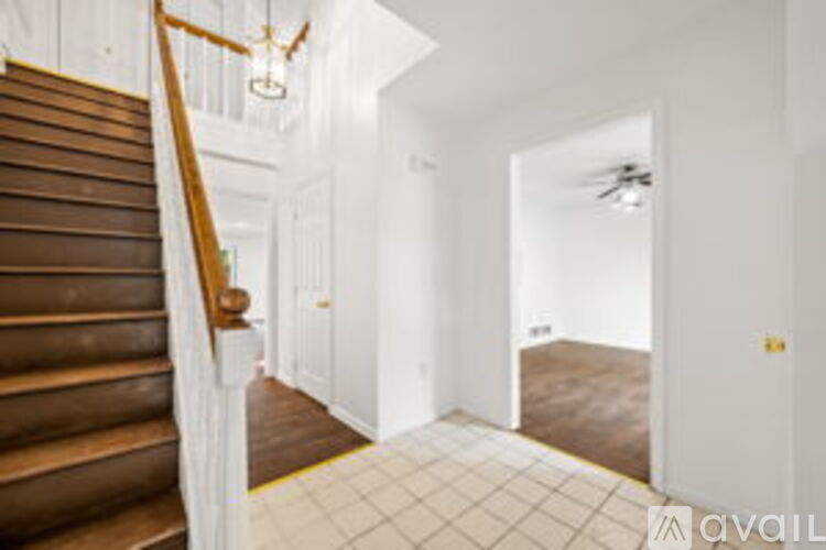 A hallway with a staircase on the left and a door on the right.