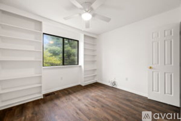 A room with a window and a fan on the ceiling.
