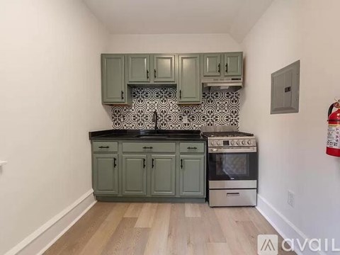 A kitchen with green cabinets and a black countertop.