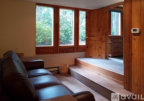 A living room with a brown leather couch and wooden floors.