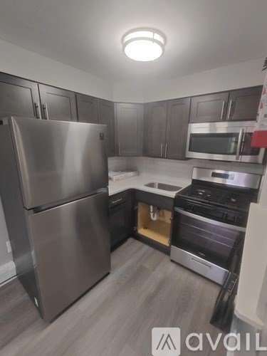 A kitchen with a stainless steel refrigerator, microwave, and oven.